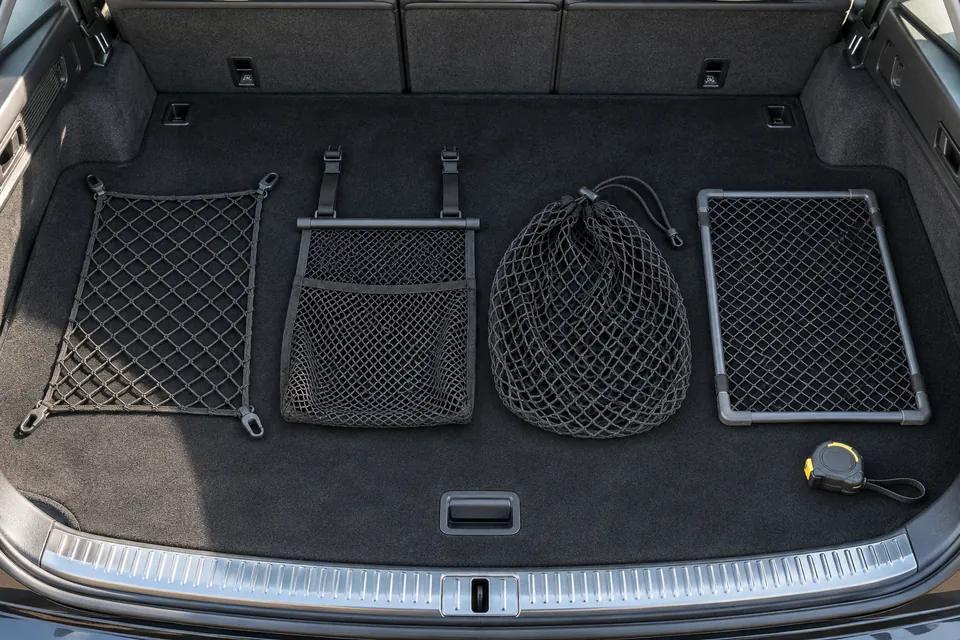 Quatre filets de coffre de voiture posés à plat et bien séparés sur un tapis de coffre : filet de sol à quatre crochets, filet vertical à poche, filet enveloppe élastique, filet de plage arrière rigide
